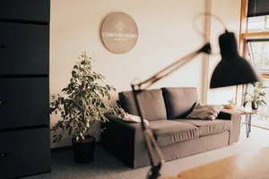 Ein Bereich des Neumünsteraner Coworking Space mit Pflanzen, einem Sofa und der Lampe eines Schreibtisches im Vordergrund.
