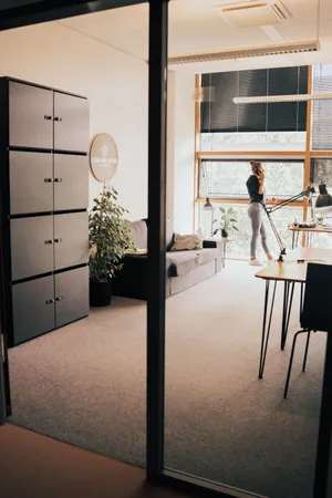 Eine Frau steht in einem Raum hinter einer Glaswand und telefoniert