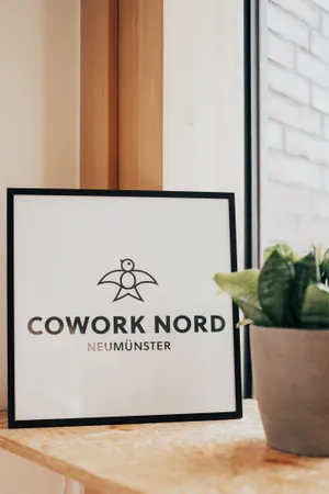 Ein Bilderrahmen mit dem Logo von Cowork Nord steht auf einem Tisch