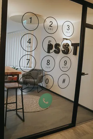 View into a meeting room through a glass door covered with a motif depicting a input field for phone numbers on smartphones.