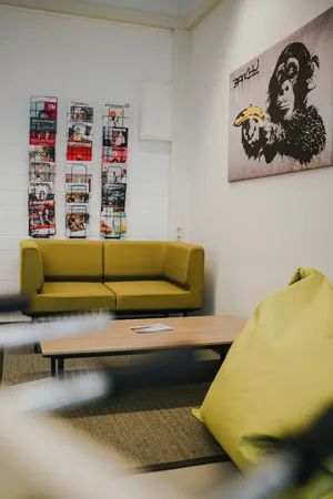 Another seating area with lots of magazines on a shelf, a sofa and beanbags.