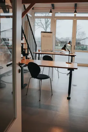 A workspace in a co-working space with a whiteboard and a large window front with a view outside in the background.
