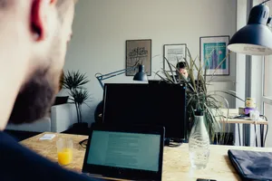 Zwei Männer sitzen sich an zwei Arbeitsplätzen gegenüber und arbeiten am Computer