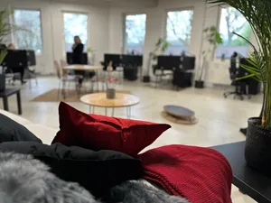 Blick vom Sofa aus auf den Raum mit mehreren Arbeitsplätzen.
