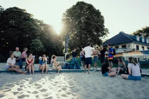 Eine Gruppe von Menschen sitzt gemeinsam bei Sonnenschein am Strand